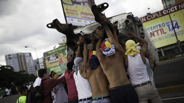Protesters overturn a truck during protests in Caracas, on Thursday.