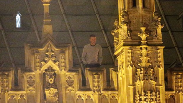 An unidentified man stands of the roof of the the British parliament, the Palace of Westminster, where he spent Saturday night. 