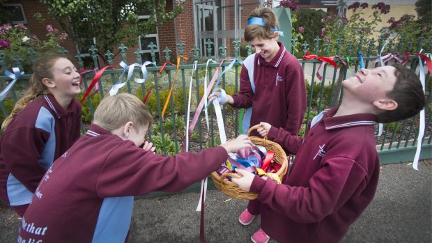 Students from the St Alipius Parish School share a funny moment while putting ribbons on the front fence of the school to acknowledge child abuse within the Catholic Church.