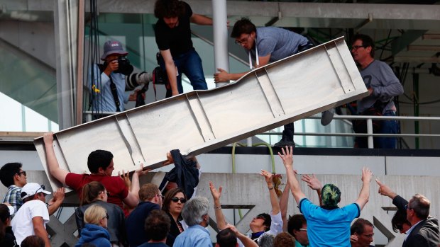 Wind chaos: Spectators help lift a piece of the roof from Court Philippe Chatrier that blew off in high winds.