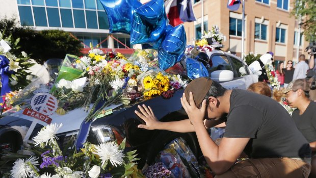 Vicente Alfaro, 15, of Irving, Texas, kneels and places his hand on a Dallas police cruiser.