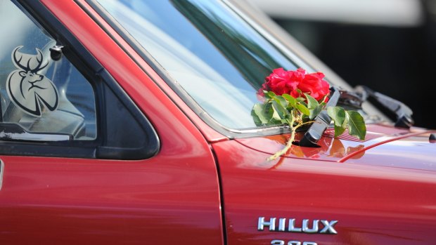 A floral tribute is laid on a 4WD out the front of the home.