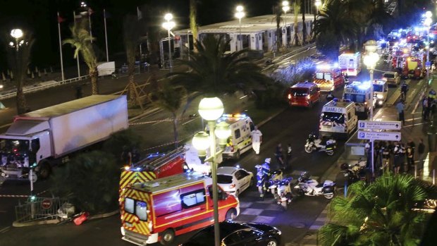 Emergency services vehicles work on the scene after a truck, left, plowed through Bastille Day revellers in the French resort city of Nice.