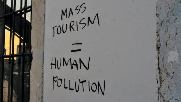 An anti-mass tourism slogan scrawled on a wall in Portugal, Lisbon.