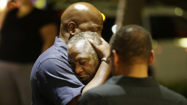 Worshippers embrace following a group prayer across the street from the scene of a shooting Wednesday.