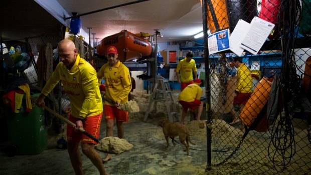 Members of the Coogee Surf Life Saving Club clear out their boatshed which was inundated with water and sand during the storms.