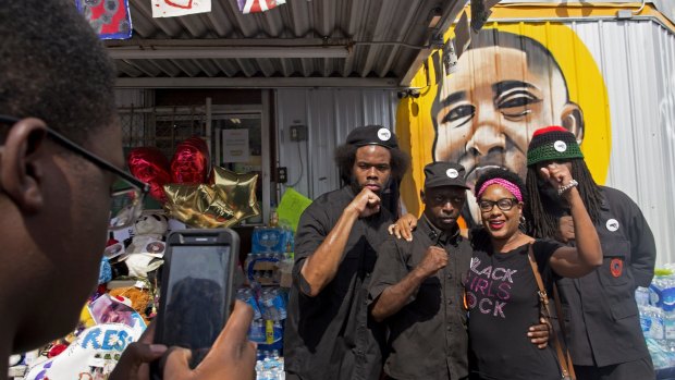 People pose for photographs with members of the New Black Panther party after they announced their intent to protest the death of Alton Sterling in Baton Rouge.