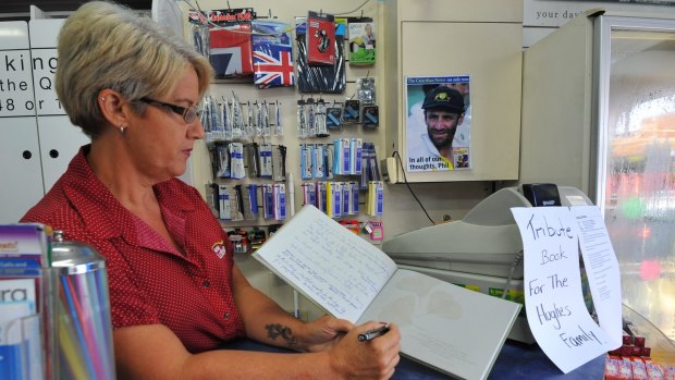 Macksville newsagent Tracey Spear with a tribute book where locals can leave a message for the Hughes family.
