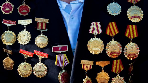 An honour guest with medals on his coat arrives to his seat to watch the parade.