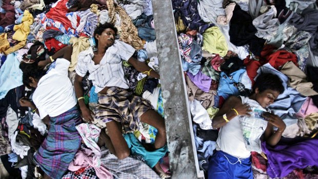 Ethnic Rohingya men take a nap on a pile of clothes donated by local residents at a temporary shelter in Langsa, Aceh province, Indonesia.