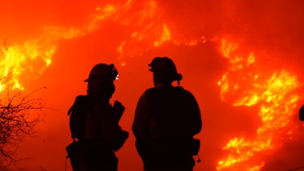 Santa Barbara firefighters keep a close eye on nearby flames atop Shepard Mesa Road in Carpinteria, California on Sunday.