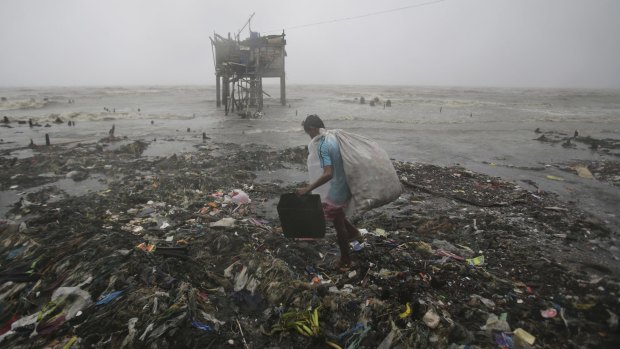 A Filipino man scavenges recyclable materials near a house on stilts as strong winds and rains caused by Typhoon Koppu hit the coastal town of Navotas, north of Manila.