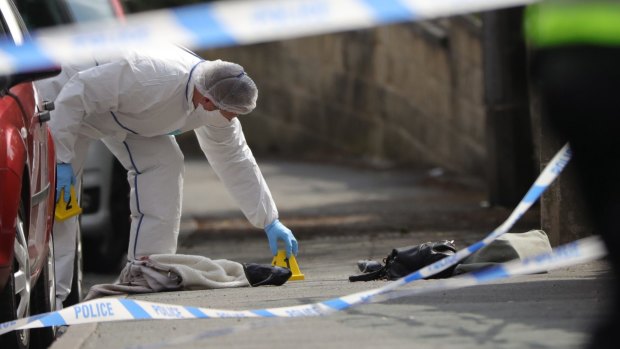 Forensic police examine shoes and a handbag at the scene.