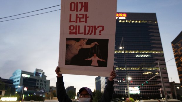 A protester holds a placard showing South Korean President Park Geun-hye as a puppet with the words "This is not a country" during a massive protest on Saturday in Seoul.