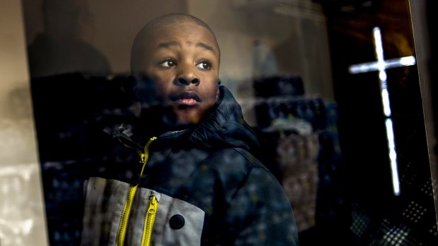 Detroit resident Jaiden Ellis, 8, looks at stacks of free bottled water to be given to the congregation while the Reverend Jesse Jackson, a civil rights leader, discusses the water crisis in Flint, Michigan. 