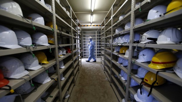 A worker leaves a room with shelves storing helmets at the tsunami-crippled Fukushima Dai-ichi nuclear power plant.