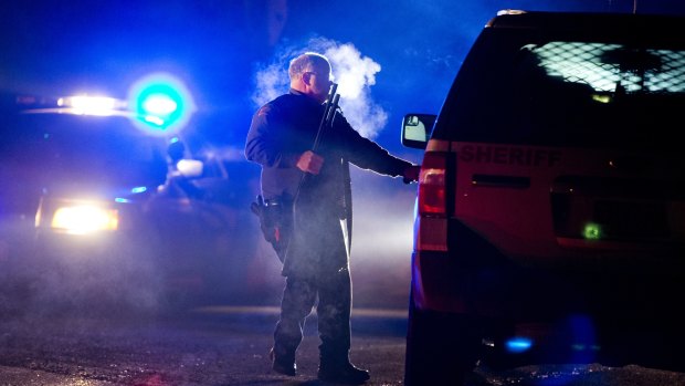 An Oregon State police officer stands by a vehicle as police officers block Highway 395 in Seneca, Oregon, on Tuesday.