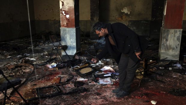 An Afghan man takes a photograph at the scene of a suicide attack on a Shiite cultural center in Kabul.