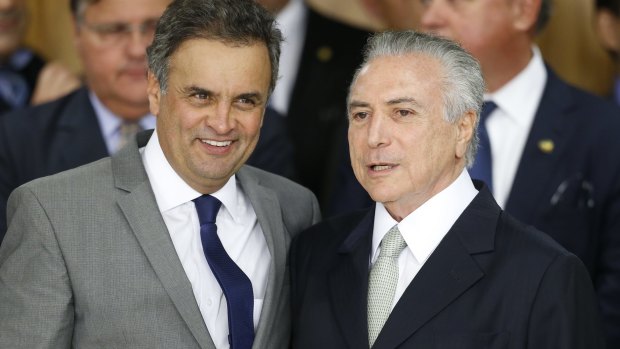 Brazil's interim President Michel Temer (right) hugs former presidential candidate Senator Aecio Neves at a signing ceremony for new government ministers. Senator Neves was narrowly defeated by Dilma Rousseff in 2014.