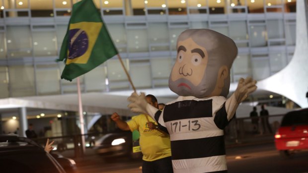 A demonstrator protests with an inflatable likeness of  Brazil's former president Lula in prison garb, in Brasilia, in March.