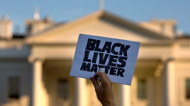 A man holds up a sign during a protest against shootings by police, at the White House in Washington. 