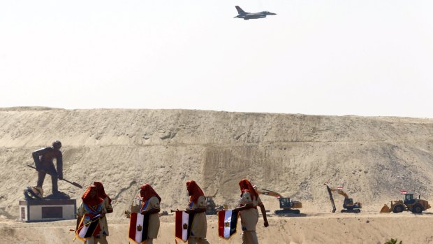 Egyptian air force planes parade and Egyptians wear Pharaonic costumes to march in front of a statue representing a man digging during the inauguration ceremony of the new Suez Canal on Thursday. 