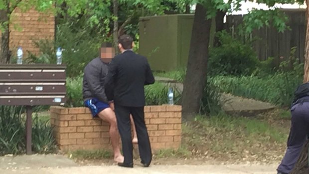 Police raids: A discussion takes place between two unidentified men outside a house at Wentworthville.