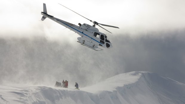 Skiers are dropped off on a ridge by helicopter.