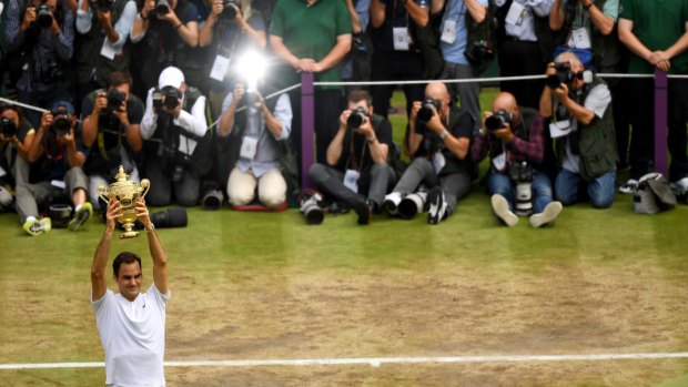 Back centre stage: Roger Federer lifts the Wimbledon trophy for the eighth time.