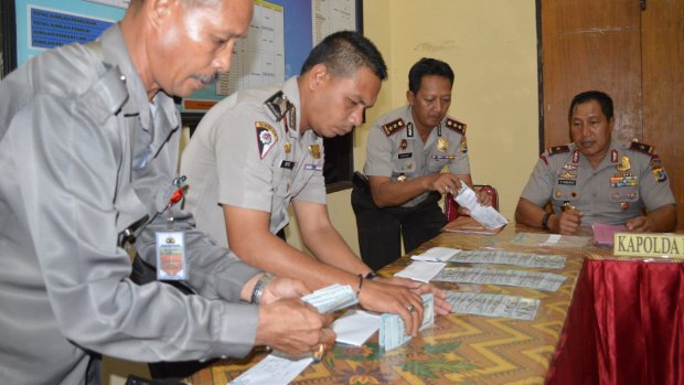 Police officers displaying six stacks of $US100 bills during a press conference by Nusa Tenggara Timur police chief Endang Sunjaya at Rote police station in June.