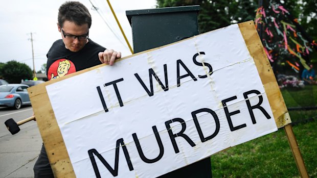 Bob Edwards uses a mallet to install a sign he made near the site where Philando Castile was shot and killed.