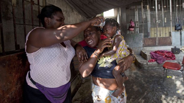 A little girl's face is washed after National Police fired tear gas near her home during protests in Port-au-Prince.