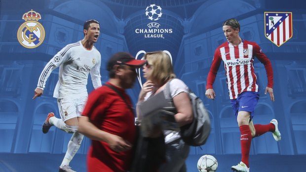 Passing interest: locals walk by a billboard portraying Real Madrid's Cristiano Ronald, left, and Athletico Madrid's Fernando Torres at the Champions Festival event area in Milan.