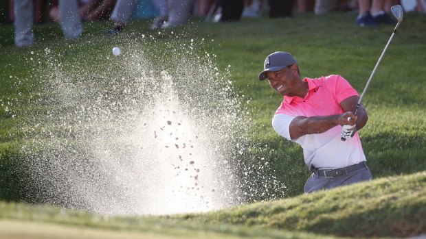 Tiger Woods hits out of a bunker on the 18th.