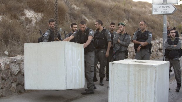 Israeli border police  help place concrete blocks on the road at the entrance to the east Jerusalem neighbourhood of Jabel Mukaber on Wednesday.