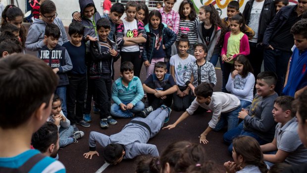 Refugee and migrant children from different countries watch on as they play a game forcing one student to do push-ups during sports class at a community learning centre at the Basilique Cathedral Saint-Espirit in Istanbul, Turkey.
