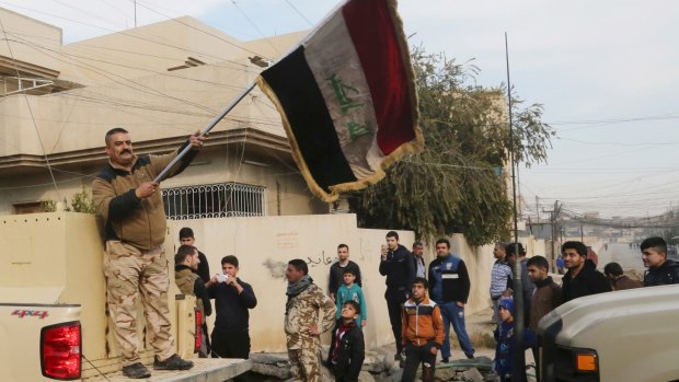 An Iraqi soldier waves the national flag as security forces patrol on the eastern side of Mosul, Iraq, on January 18.