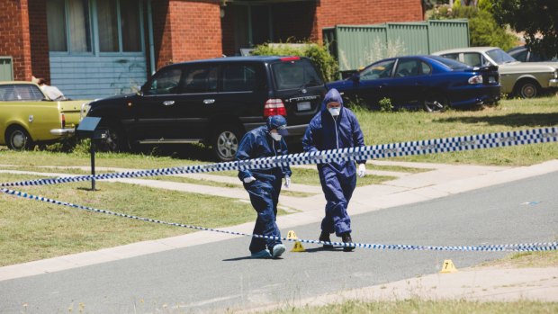 Forensics officers examine markers on Goodenia Street, Rivett, after a man died on Sunday.