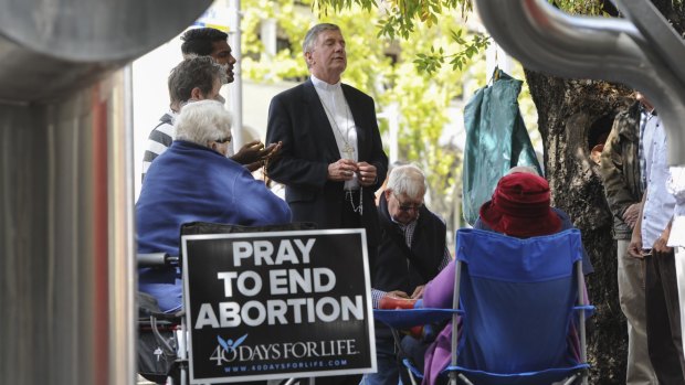 Catholic Archbishop of Canberra and Goulburn Christopher Prowse, centre, attends a prayer vigil outside the Moore Street abortion clinic in March.