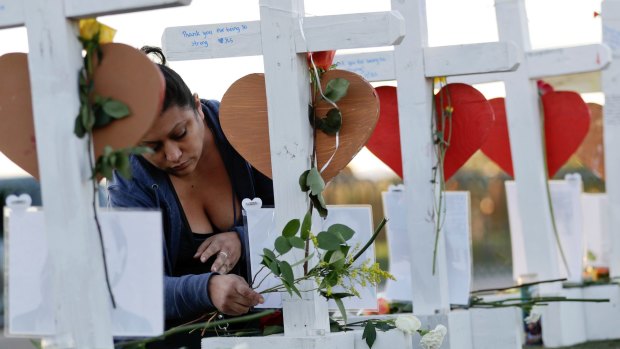 Cece Navarrette places flowers at a cross for her cousin, Bailey Schweitzer, who was among those killed during the mass shooting in Las Vegas.
