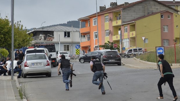 Turkish police officers run for cover during a gunfight near the site of an overnight explosion at a police station in Istanbul.