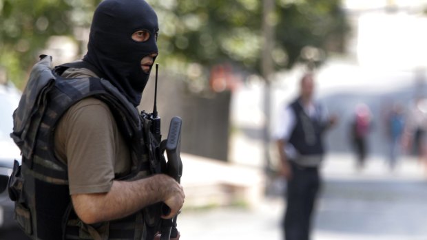 A masked Turkish police officer secures a road leading to the US Consulate building in Istanbul.