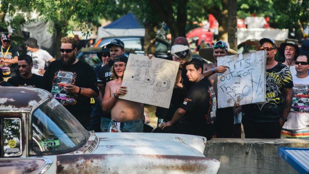 Men hold up signs along Tuff Street during Summernats. 