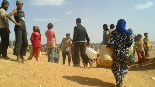 Syrian refugees gather for water at the Rukban refugee camp near Jordan's north-east border with Syria. 