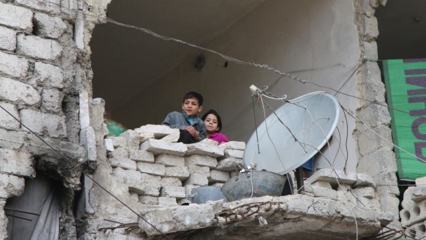 Children peer out from their destroyed home in Aleppo, Syria's largest city.
