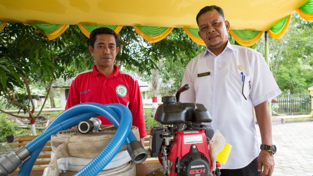 The Fire-Free Village program's local liaison (left) and Pelalawan's deputy head of village, Edi Hanafi, with the motorised water pump the village bought with the program's half-reward.