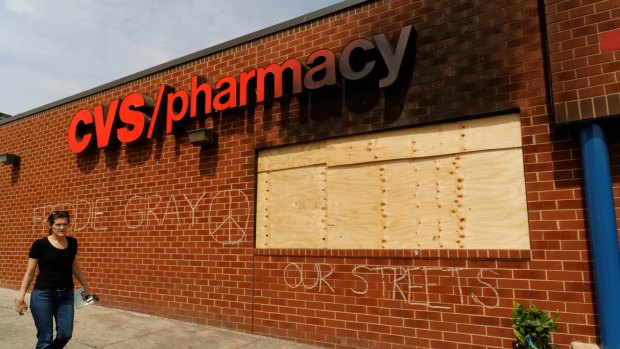 A woman walks past a Baltimore pharmacy looted during the protests over the death of Freddie Gray.