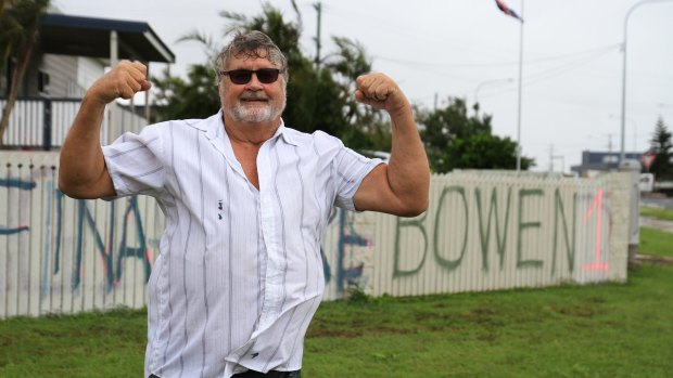 Graham Wilson of Bowen paints a fresh message on his fence in the wake of Cyclone Debbie.