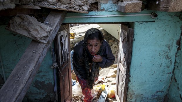 An earthquake survivor visits her collapsed house in Sankhu, on the outskirts of Kathmandu, on Tuesday.