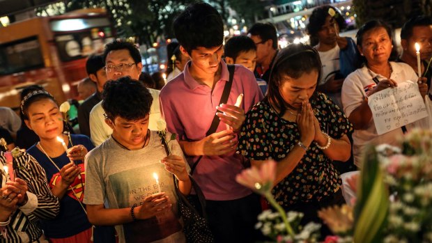 People light candles and pray for the victims of a bomb blast at the re-opened Erawan shrine in Bangkok on Wednesday.